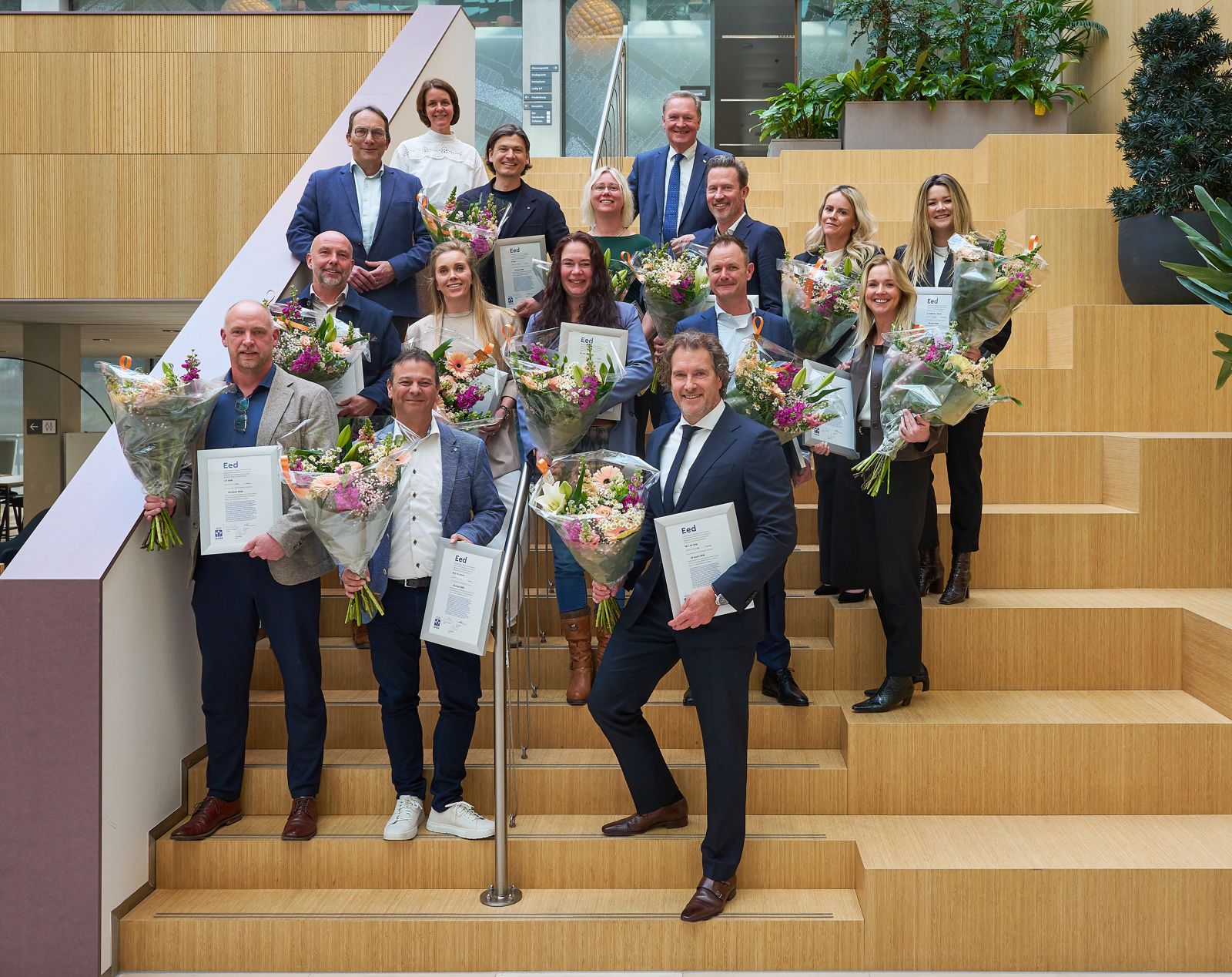 NVM-leden met certificaat en bloemen op een houten trap